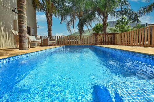 a blue swimming pool with a fence and palm trees at וילה גאיה בכנרת-VIILA GAYA in Migdal