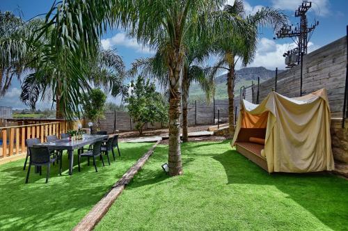 a garden with a couch and a table and palm trees at וילה גאיה בכנרת-VIILA GAYA in Migdal