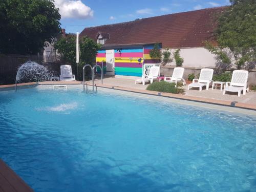 una grande piscina con sedie bianche e un edificio di Gîte La Grange 9 pers a Saint-Georges-sur-Cher