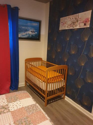 a baby crib in a room with a blue wall at Couleurs des îles in Le Tampon