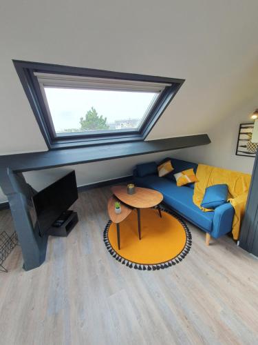 een woonkamer met een blauwe bank en een tafel bij Lodge de la Gare Vue Cathédrale in Rouen