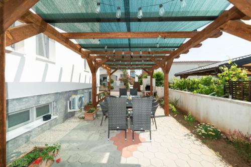 a patio with a table and chairs under a wooden pergola at Crowonder Luxury Vir- 6 New Apartments for Families with Playground for Kids in Vir