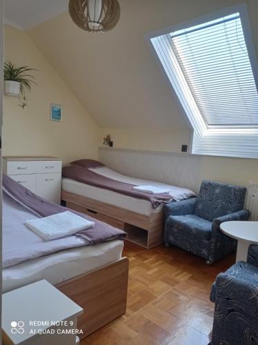 a bedroom with two beds and a chair and a window at Akác Vendégház in Eger