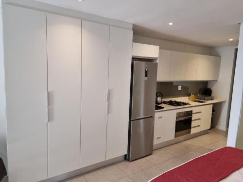 a kitchen with white cabinets and a stainless steel refrigerator at OCEANDUNE SIBAYA G023 Block D in Umhlanga