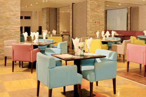 The Leela Hotel في دبي: مطعم فيه طاولات وكراسي في الغرفة