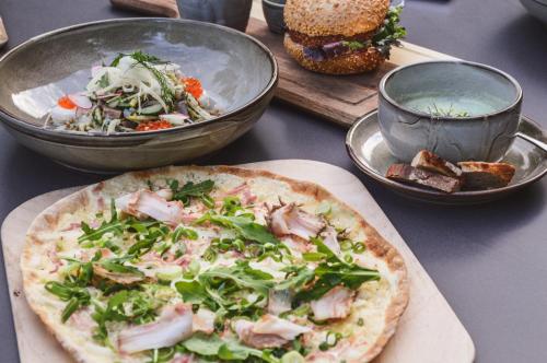 a pizza on a table with a salad and a sandwich at Das Achental Resort in Grassau