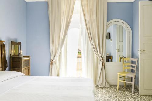 a bedroom with a bed and a mirror and a chair at Palazzo Dante B&B Racale in Racale