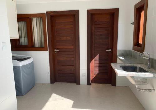 a bathroom with two sinks and two wooden doors at Casa 4 Quartos Praia do Forte in Praia do Forte