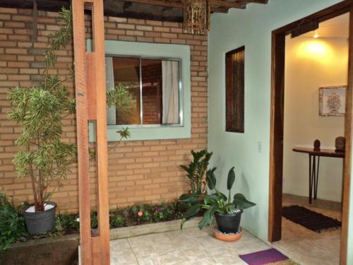 a room with potted plants and a brick wall at Pousada Alfa e Ômega in Alto Paraíso de Goiás