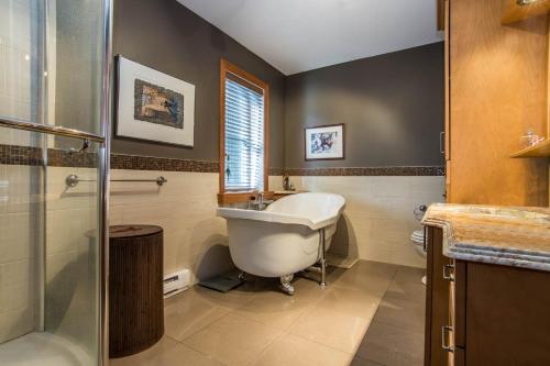 a bathroom with a tub and a sink and a shower at Au Sommet du Lac Magog in Magog-Orford