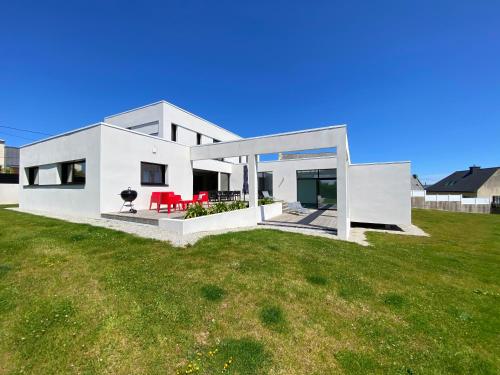 une maison blanche avec une pelouse verte dans l'établissement Villa Pool and Beach Bretagne, à Plouescat