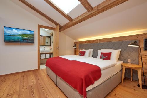 a bedroom with a large bed with a red blanket at Das Achental Resort in Grassau