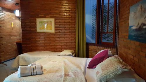 a bedroom with two beds and a brick wall at Pousada Alfa e Ômega in Alto Paraíso de Goiás