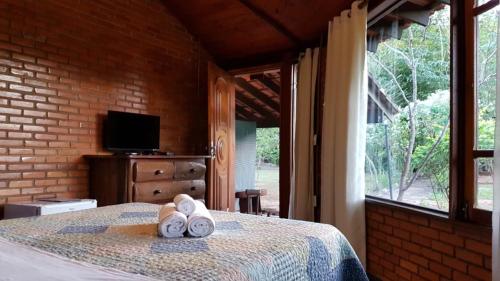 1 dormitorio con 1 cama con 2 toallas en Pousada Alfa e Ômega, en Alto Paraíso de Goiás