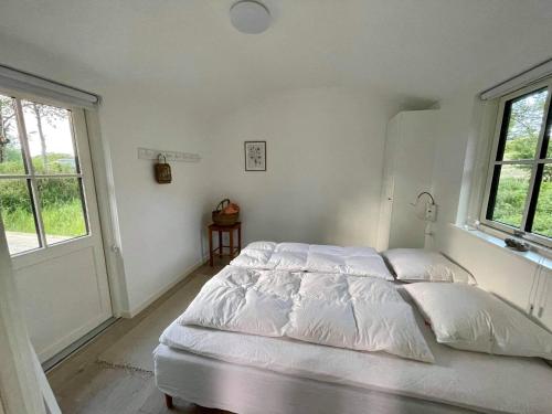 a white bedroom with a bed and two windows at Sommerhus Mossø in Skanderborg