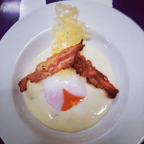 a plate of food with bacon and eggs on it at Hotel Flora in Cesenatico