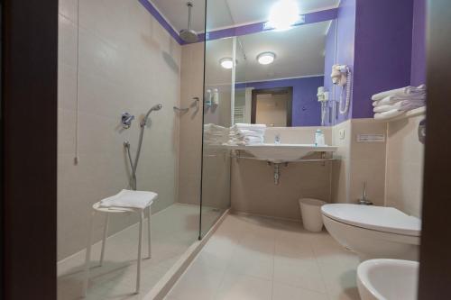 a bathroom with a shower and a toilet and a sink at Kona Hotel Verona by Kleos Group Collection in Negrar
