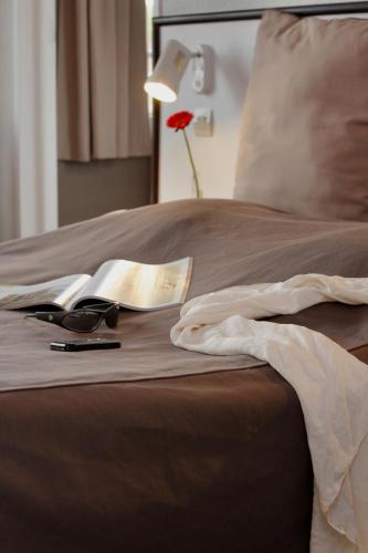 a bed with a book and glasses and a lamp at Le Normandy in Wissant