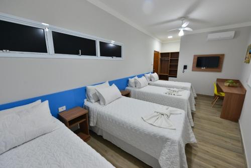 a hotel room with two beds and a table at Vinds Economic Hotel in Ipatinga