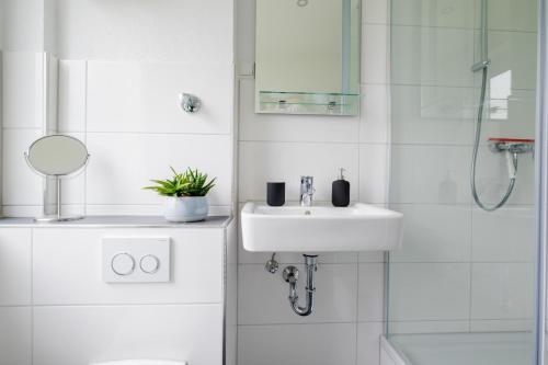 Un baño blanco con lavabo y ducha. en cruwzo I Apartment Rüttenscheid- Grün & Zentral, en Essen