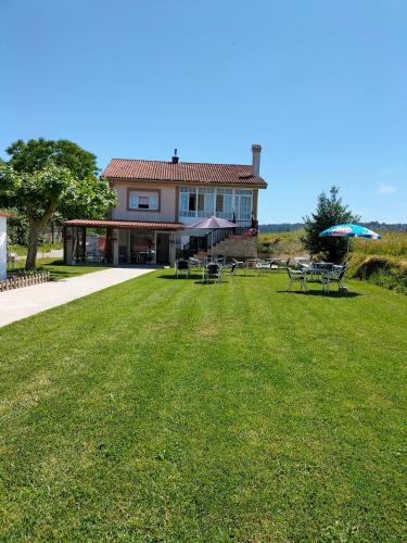 a house with a lawn with tables and umbrellas at Pension Diana in O Pedrouzo