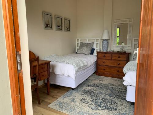 a bedroom with a bed and a dresser and a mirror at Trinity Farm Ocean view Cottage in Plettenberg Bay