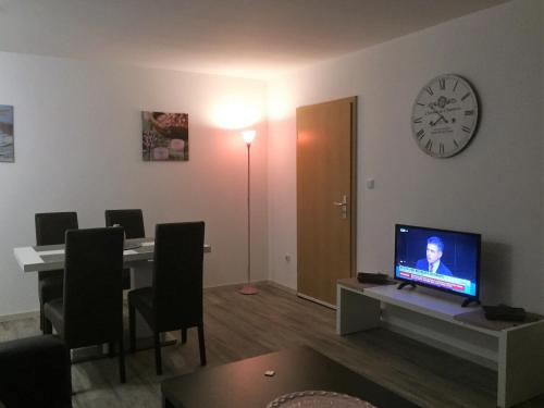 a living room with a desk with a television and a clock at Haus am Burggraben in Hinte