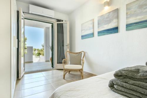 ein Schlafzimmer mit einem Bett, einem Stuhl und einem Fenster in der Unterkunft Modern stylish bungalow in Moraira in Moraira