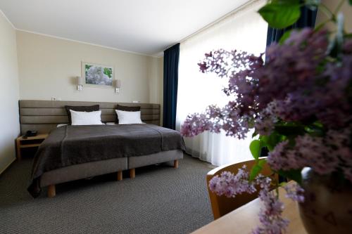 a bedroom with a bed and a window with purple flowers at Spa Hotel Ezeri in Sigulda