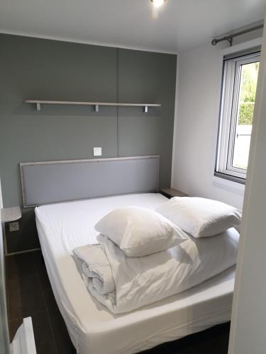 un lit avec des draps blancs et des oreillers dans une chambre dans l'établissement Le Clos Tranquille, à Gonneville-en-Auge