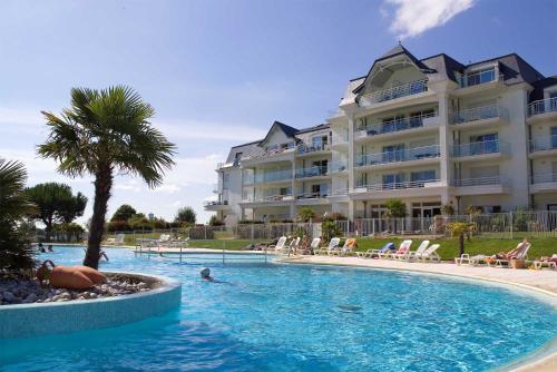 une piscine en face d'un grand bâtiment dans l'établissement Madame Vacances Les Maisons de Fontenelles, à LʼAiguillon-sur-Vie