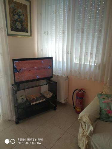 a living room with a flat screen tv on a stand at Porto Maria Holiday Home in Yerakiní