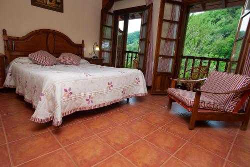 a bedroom with a bed and a chair and windows at Posada Peñas Arriba in Lon