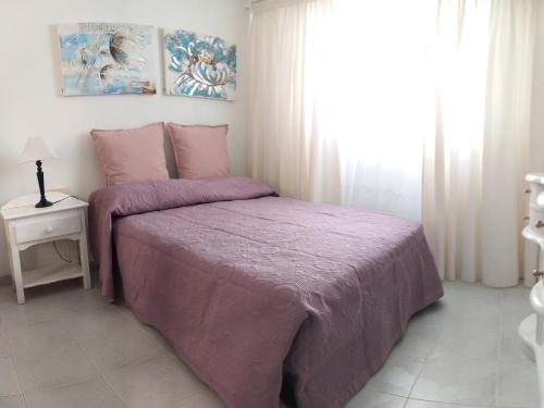 a bedroom with a purple bed and a window at Casa Érika in Puerto del Rosario