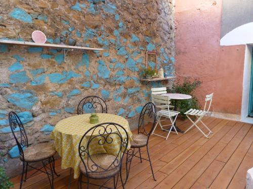 une table et des chaises sur une terrasse avec un mur en pierre dans l'établissement Maison Mômes, à Bize-Minervois