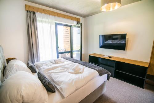 a bedroom with a bed with a window and a tv at Apartmány Tatry Žiarce in Liptovský Mikuláš