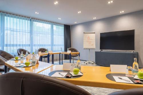 a conference room with a table and chairs and a screen at ACHAT Hotel Suhl in Suhl