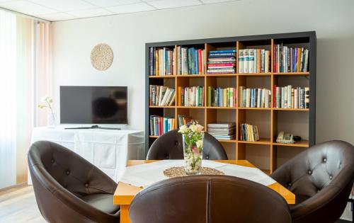 a dining room with a table and chairs and a book shelf at ACHAT Hotel Suhl in Suhl