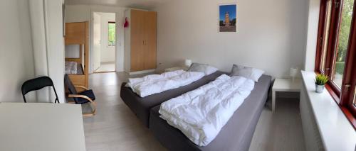 a living room with two beds with white sheets at Oasen Samsø in Nordby