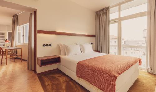 a bedroom with a bed and a table and a window at Ceuta Terrace Suites in Porto