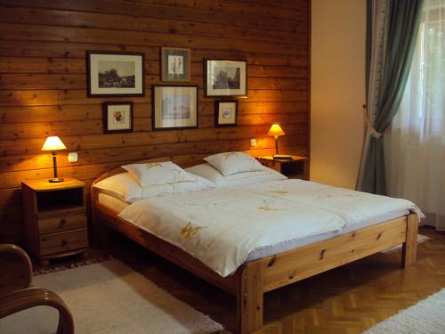 sypialnia z dużym łóżkiem i drewnianymi ścianami w obiekcie Tölgyes Apartment w Hajduszoboszlo
