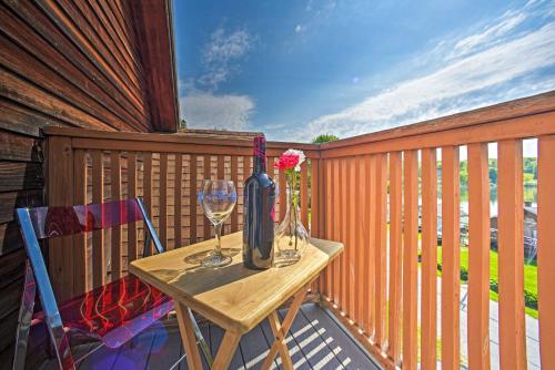 a table with wine glasses and a vase on a balcony at Lakeside Berkshires Home Near Hiking and Skiing! in Lanesborough