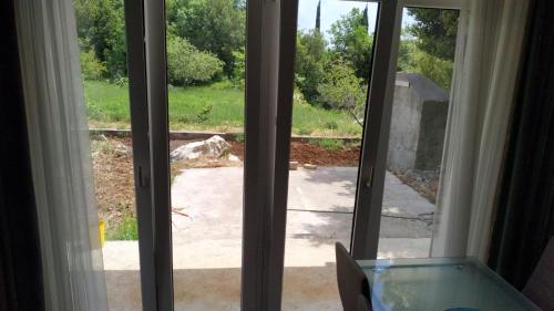 an open sliding glass door with a view of a yard at Airport Garden Apartments in Čilipi