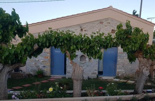 una casa con puertas azules y árboles delante de ella en Laini Guest Houses, en Koulkouthianá