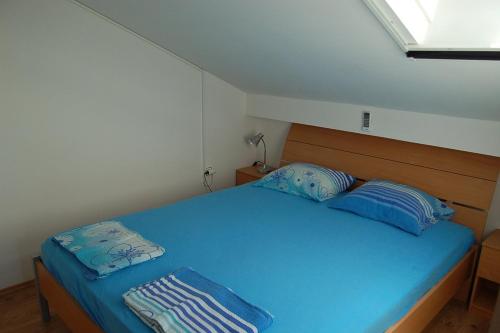 um quarto com uma cama azul e 2 almofadas em Apartment in Privlaka with Terrace, Air conditioning, WIFI, Washing machine (4839-2) em Privlaka