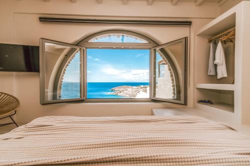 een slaapkamer met een groot raam met uitzicht op de oceaan bij Casa Eutopia in Agios Romanos
