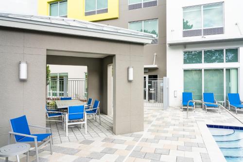 a patio with blue chairs and a table and a pool at Holiday Inn Express Doral Miami by IHG in Doral