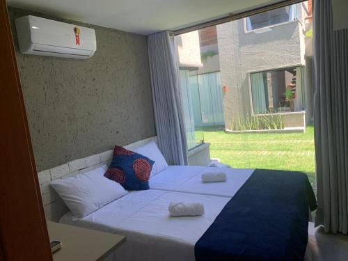 a bed in a room with a large window at Vila dos Milagres Casa de Charme in São Miguel dos Milagres