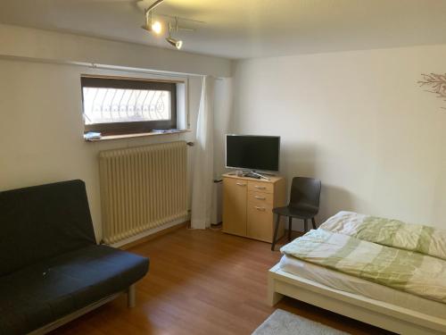 Schlafzimmer mit einem Bett, einem TV und einem Stuhl in der Unterkunft ruhiges privates Zimmer in Freiburg, zentrumsnah, Nähe Europapark in Freiburg im Breisgau