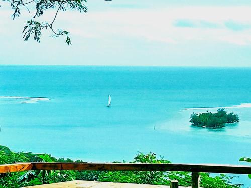 a sailboat in the ocean with a small island at Sunset rooms - Auberge Polynésienne in Tevaitoa